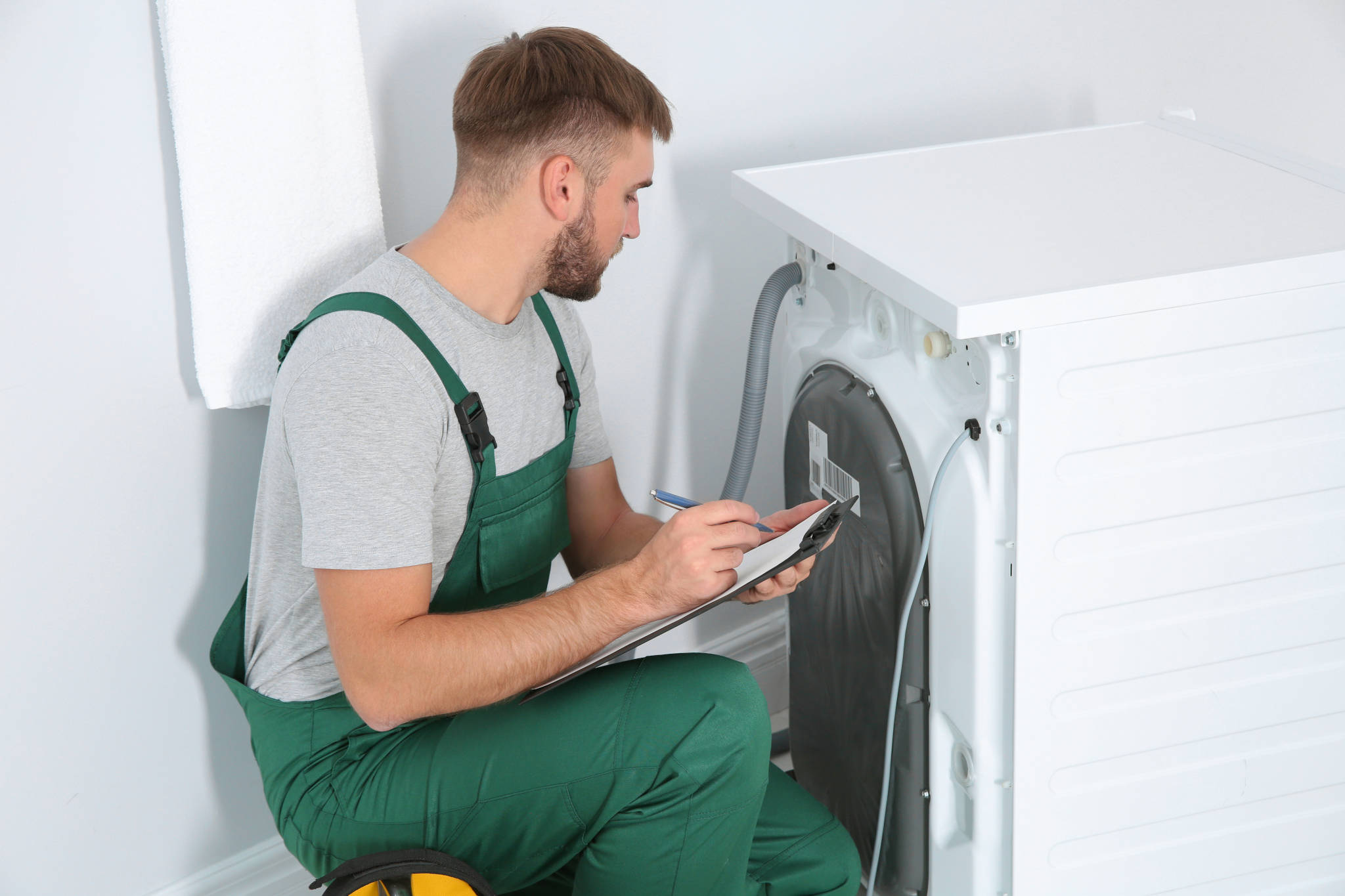 Appliance repair technician inspecting a clothes dryer to diagnose overheating or sensor issues.
